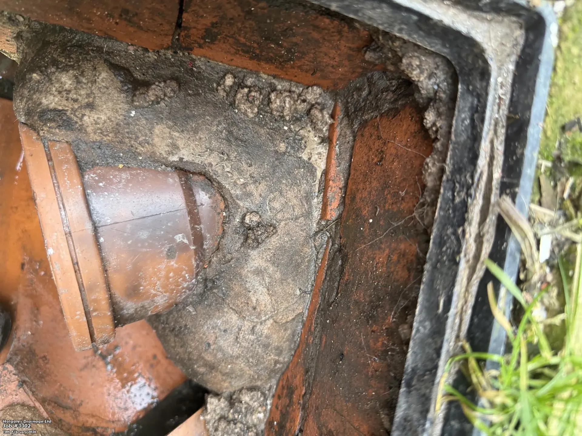 A brick drainage manhole with a plastic pipe and debris buildup, suitable for a drain inspection service page.