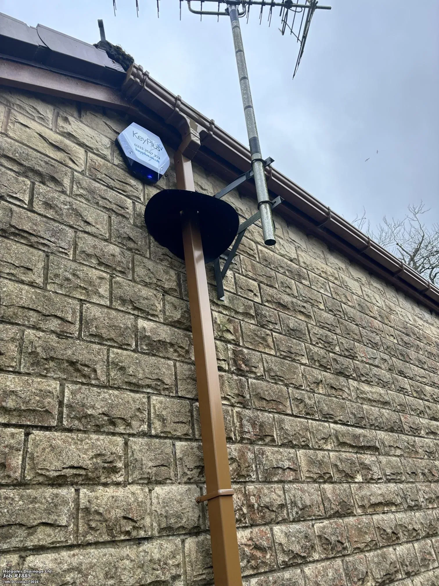 Professional rodent proofing showing a cone-shaped rat guard installed on a brown drainpipe of a stone-walled house in Blackburn.