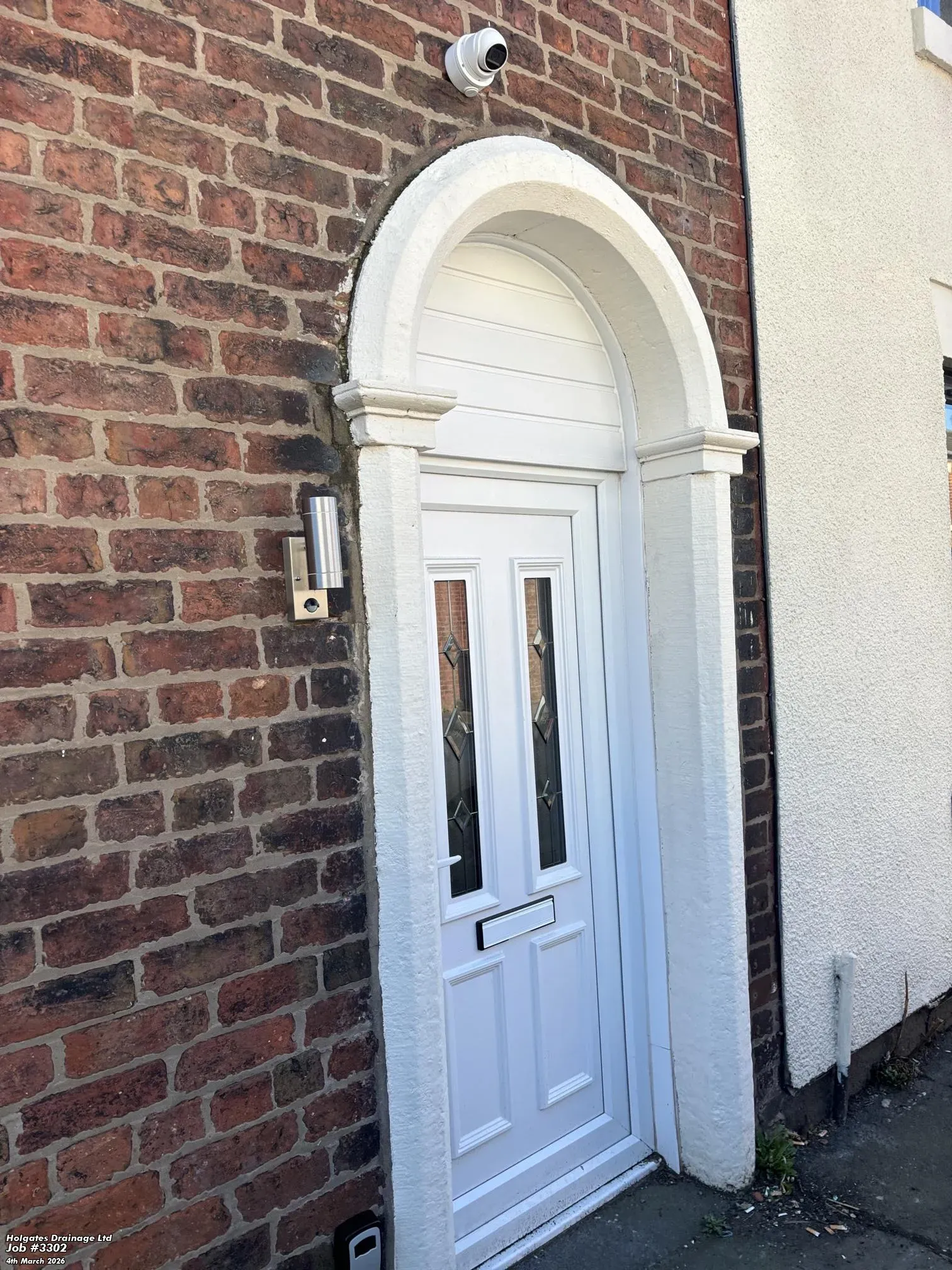Exterior of a residential property with a white arched door and red brick walls in Lancashire