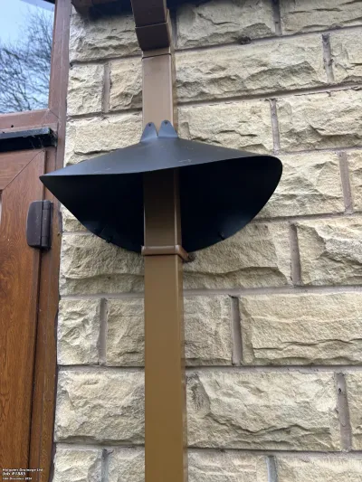 Black rodent baffle installed on a brown downpipe for pest proofing a stone property