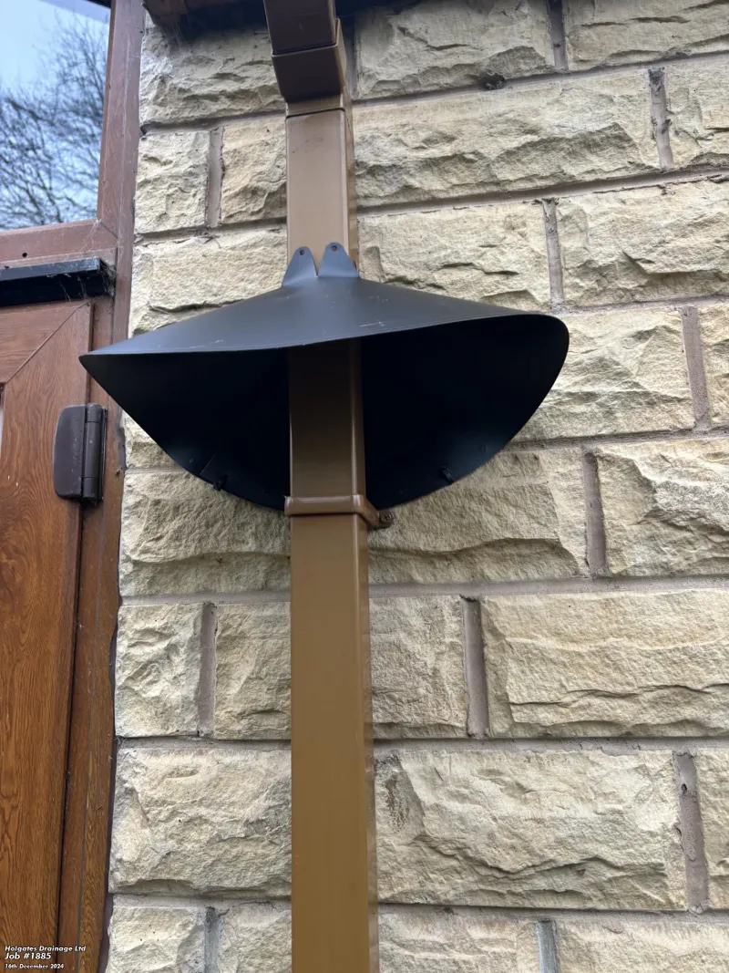 Black rodent baffle installed on a brown downpipe for pest proofing a stone property