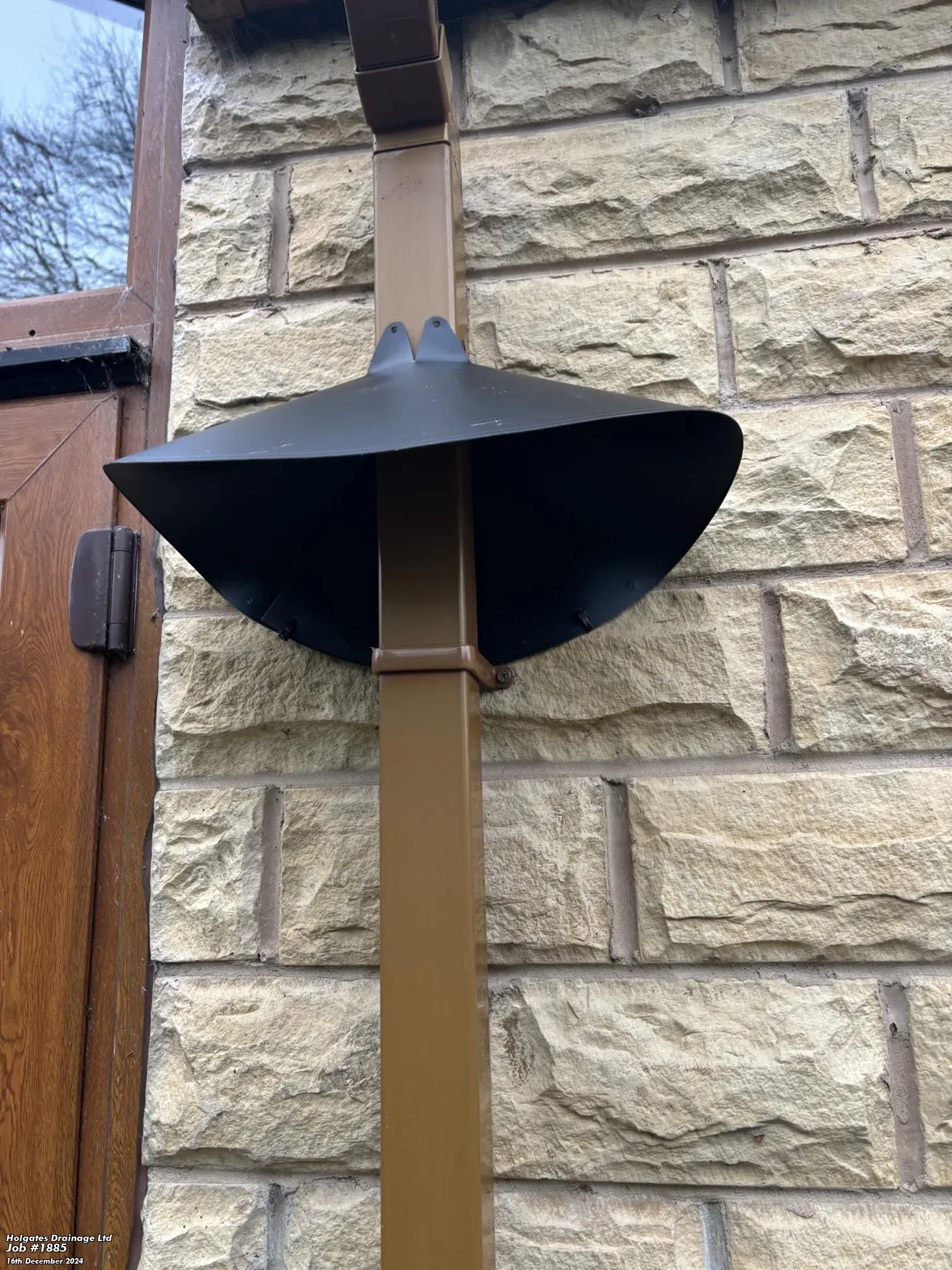 Black rodent baffle installed on a brown downpipe for pest proofing a stone property